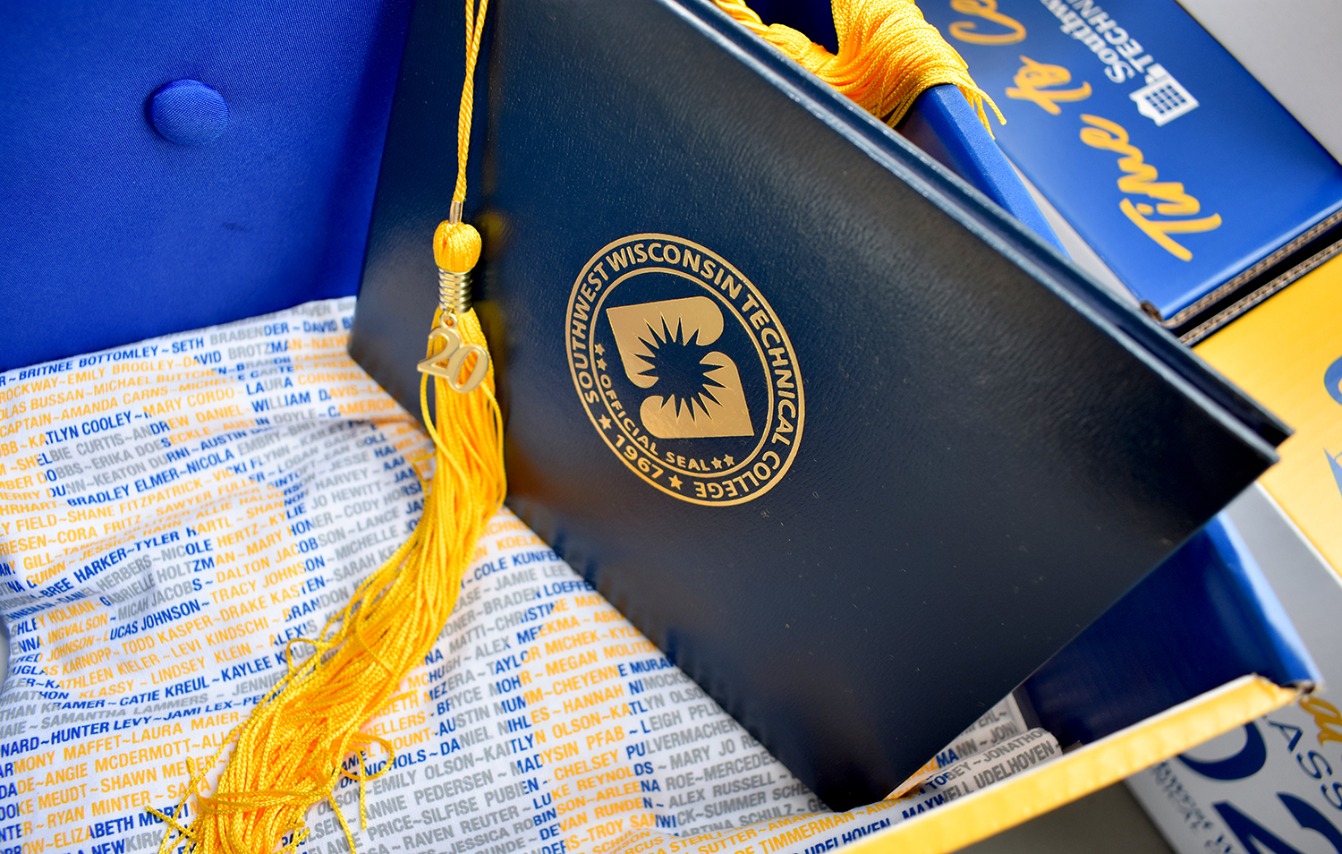 Blue diploma cover with yellow tassle atop t-shirt