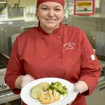 Woman is red chef's uniform holding food