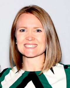 Woman smiling with green, white and black shirt, headshot.