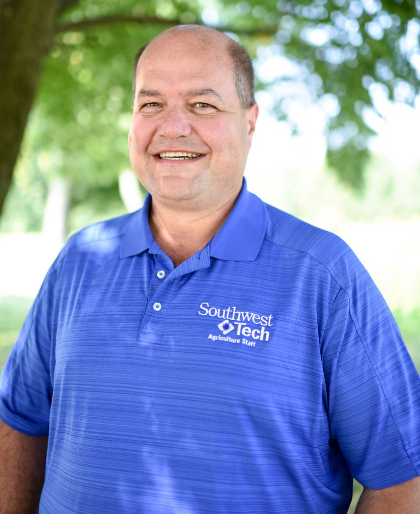 Man in blue Southwest Tech golf shirt in front of tree