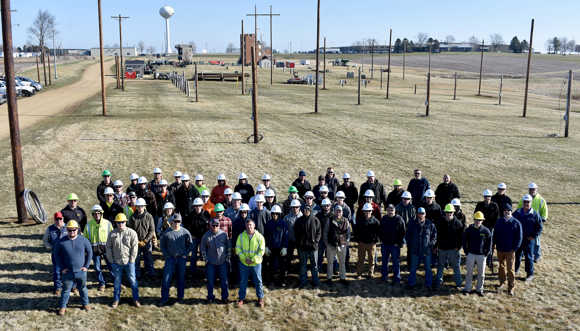 The group of lineworker students stand in the pole field.