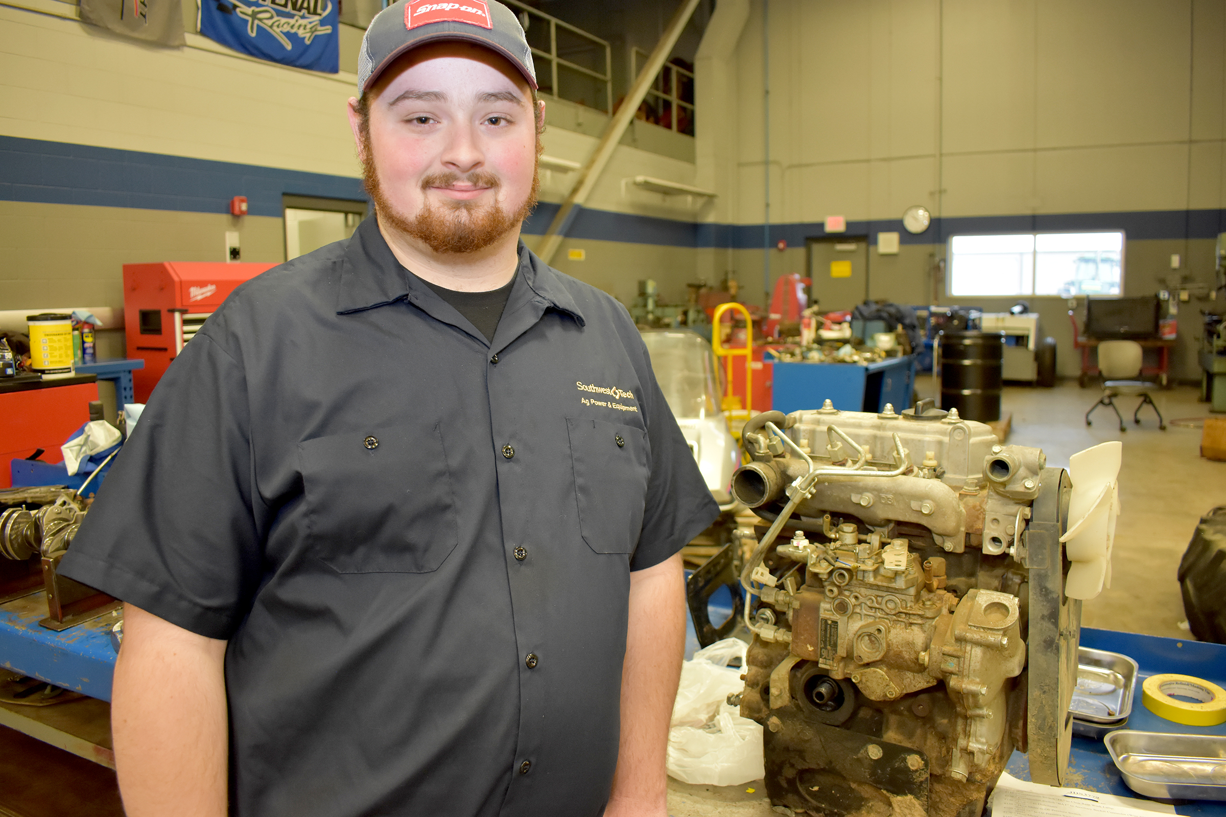 Male ag student standing in front of engine.