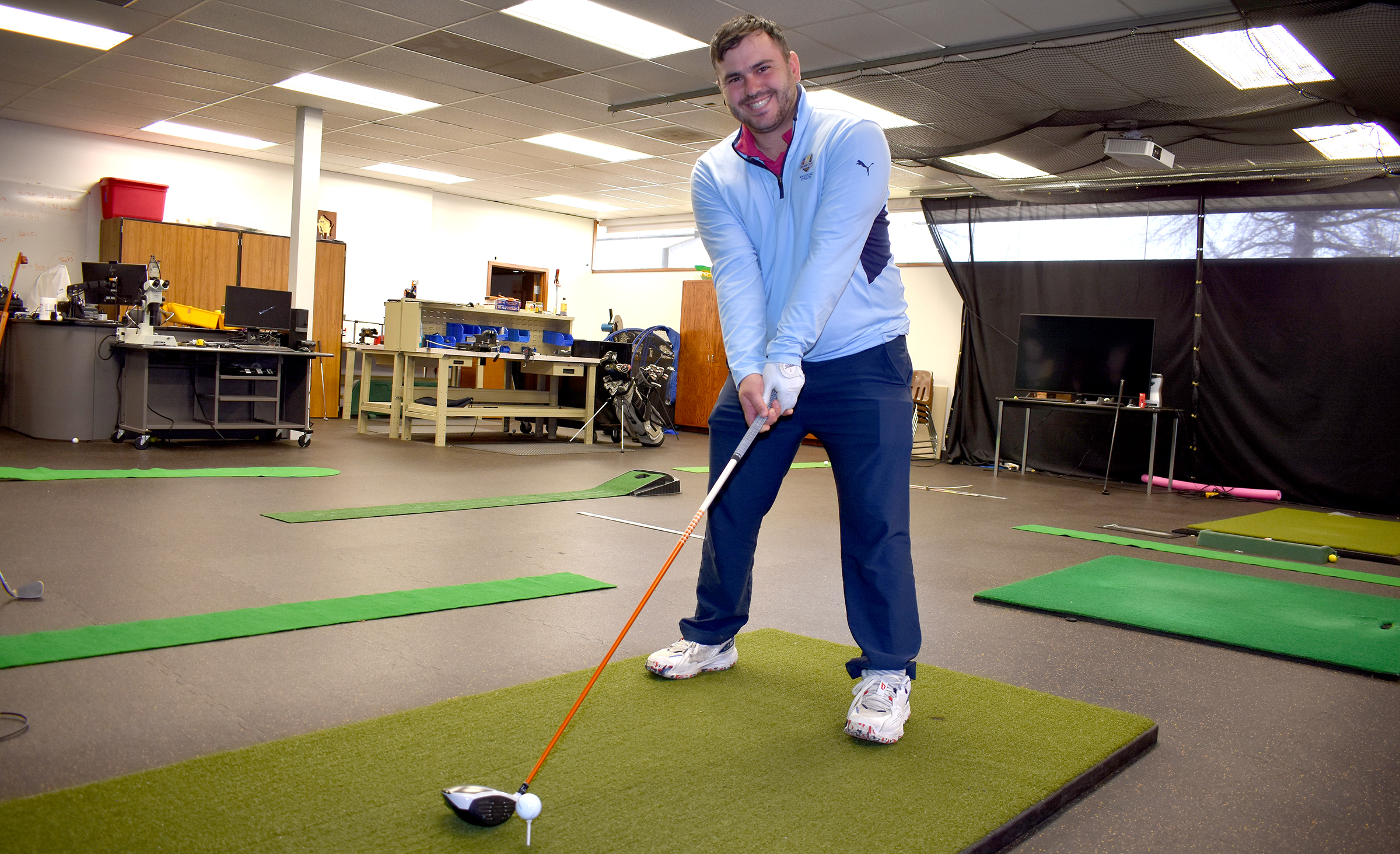 Golf student in the golf lab pretending to tee off.