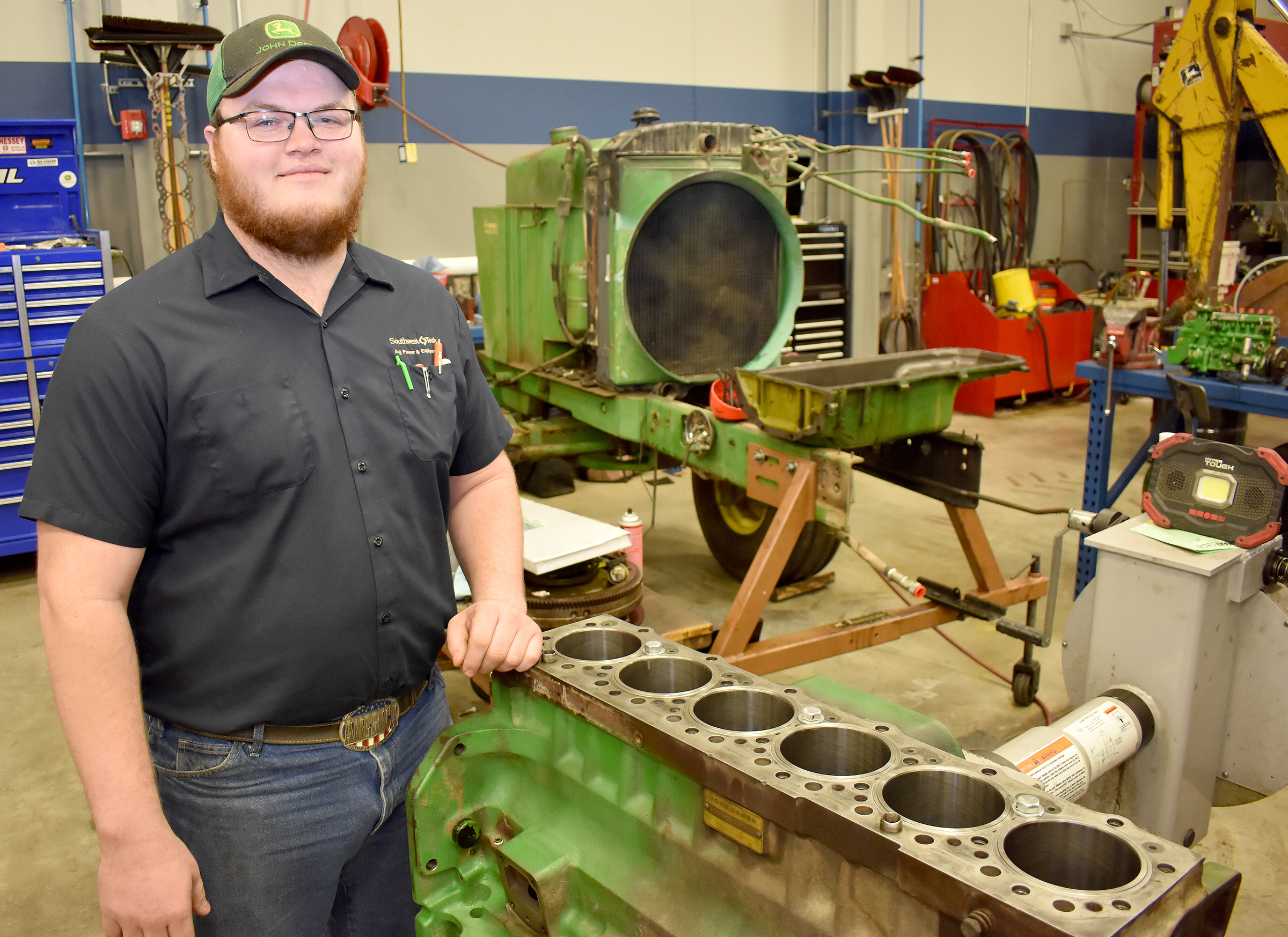 Male student standing next to tractor engine.