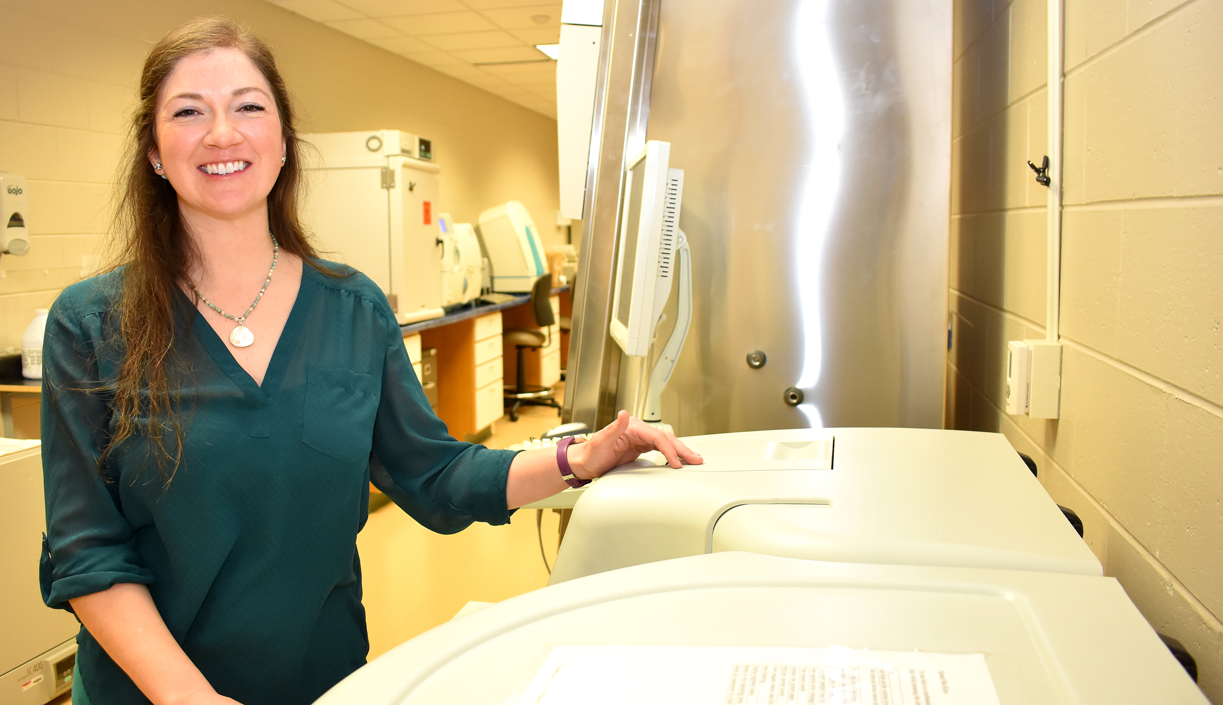 Female student standing next to medical lab equipment.