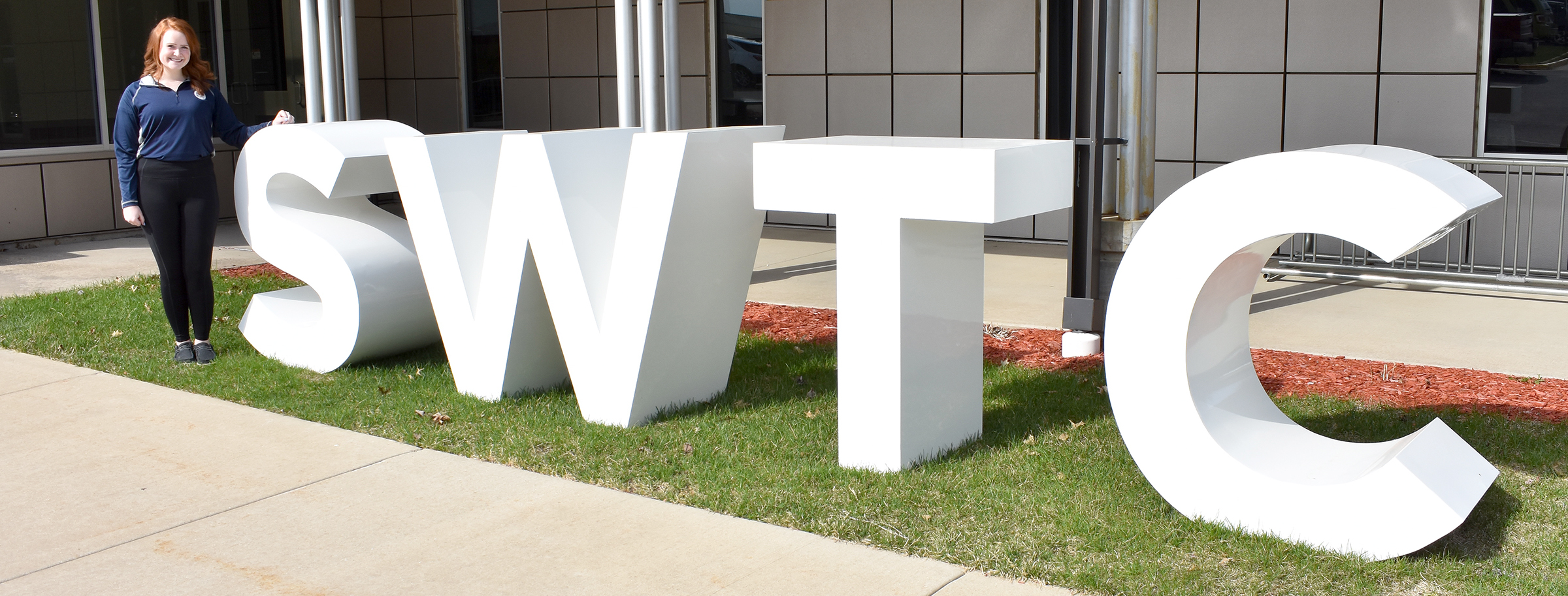 Female student standing next to large S-W-T-C letters