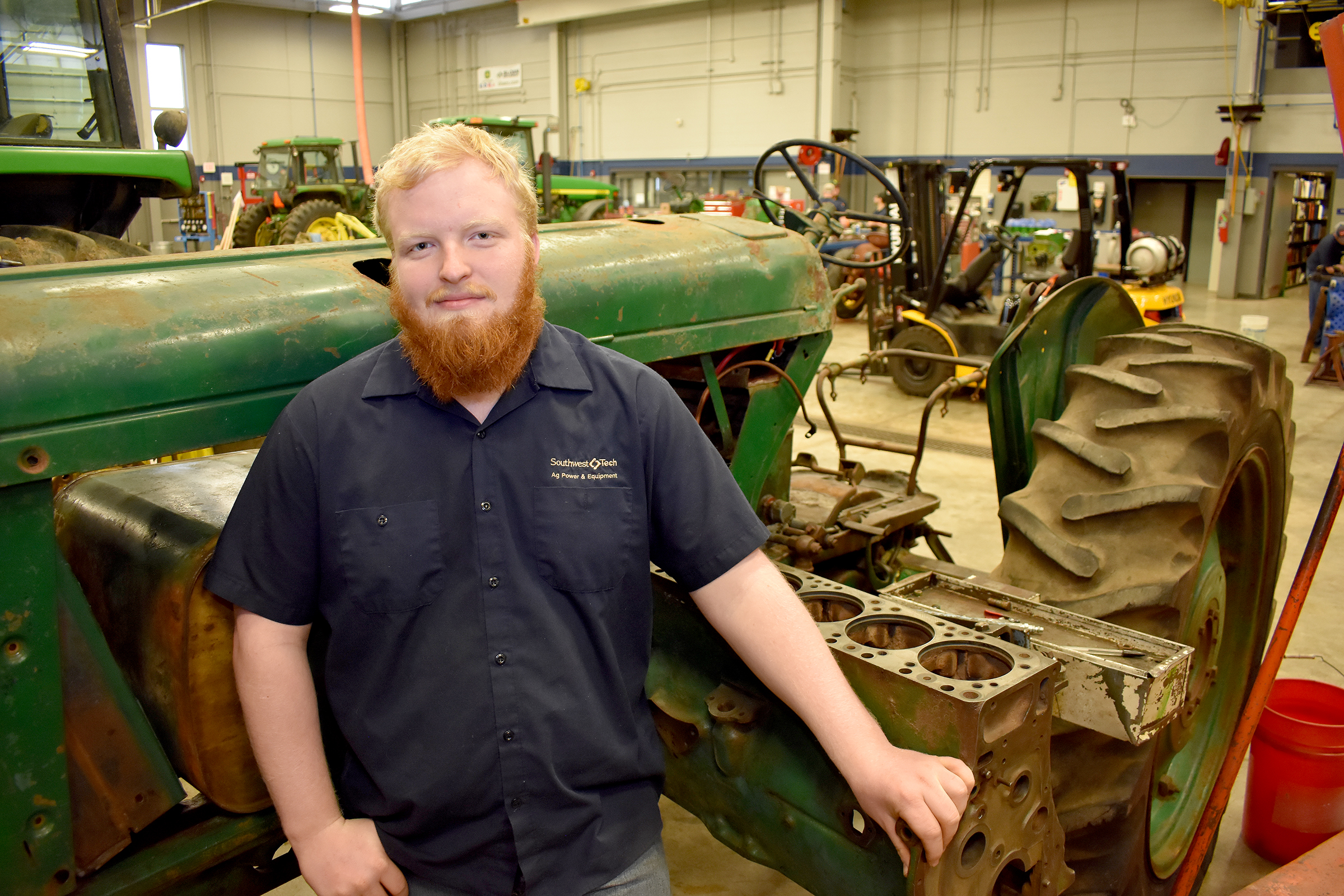 Ag Power student standing in front of older green tractor.