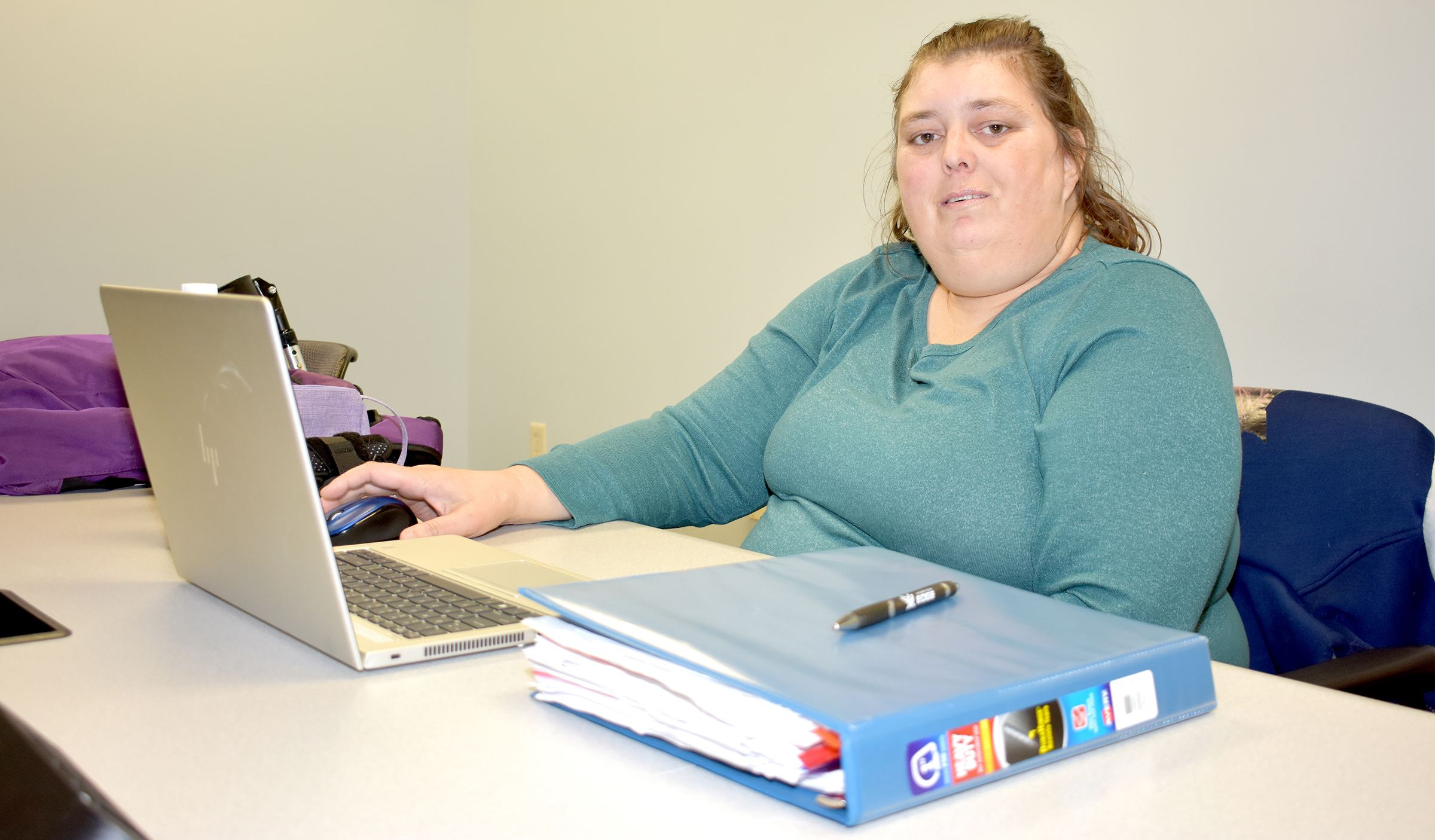 Female student sitting behind desk, laptop on desk.