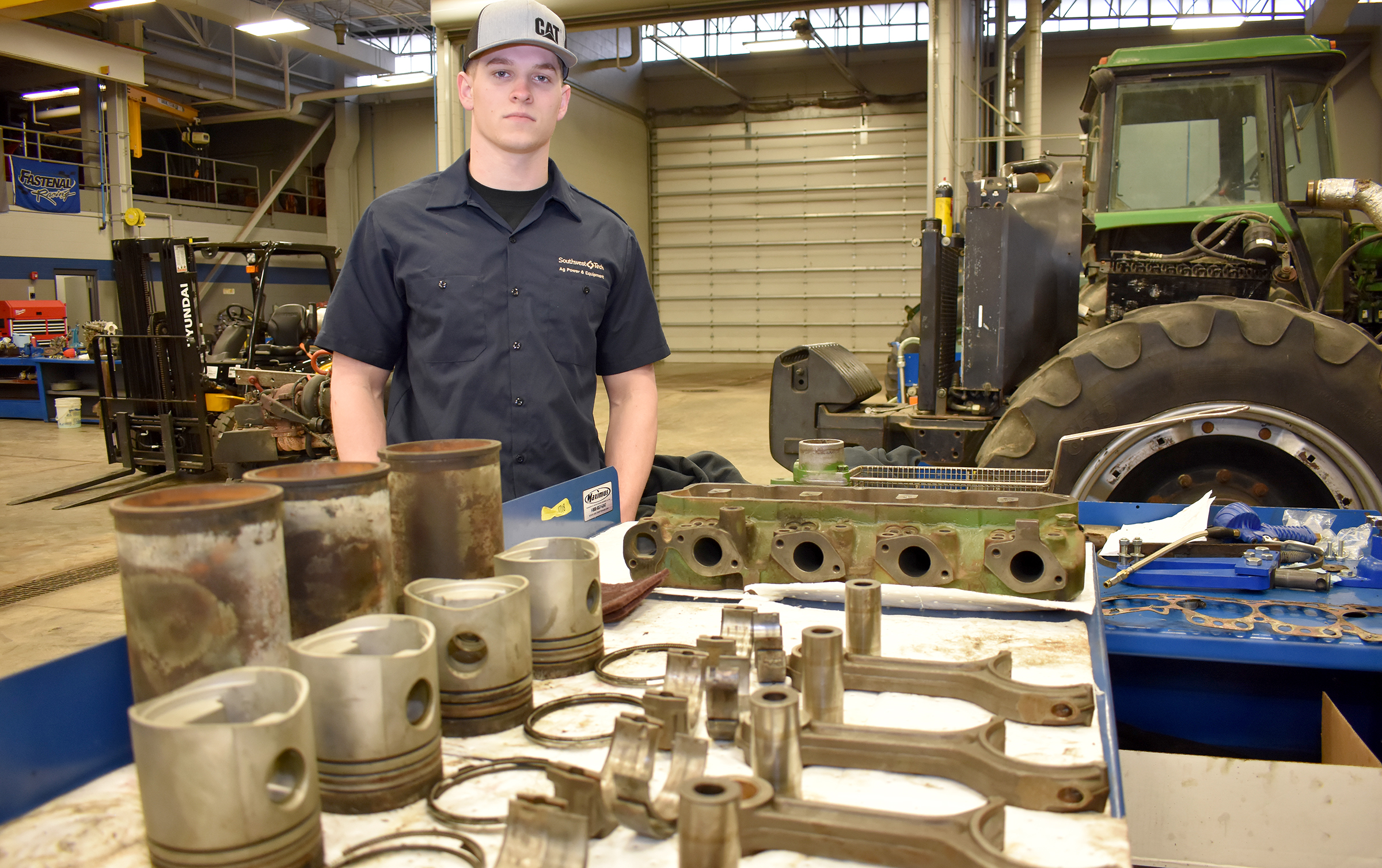 Male ag student standing behind engine parts.