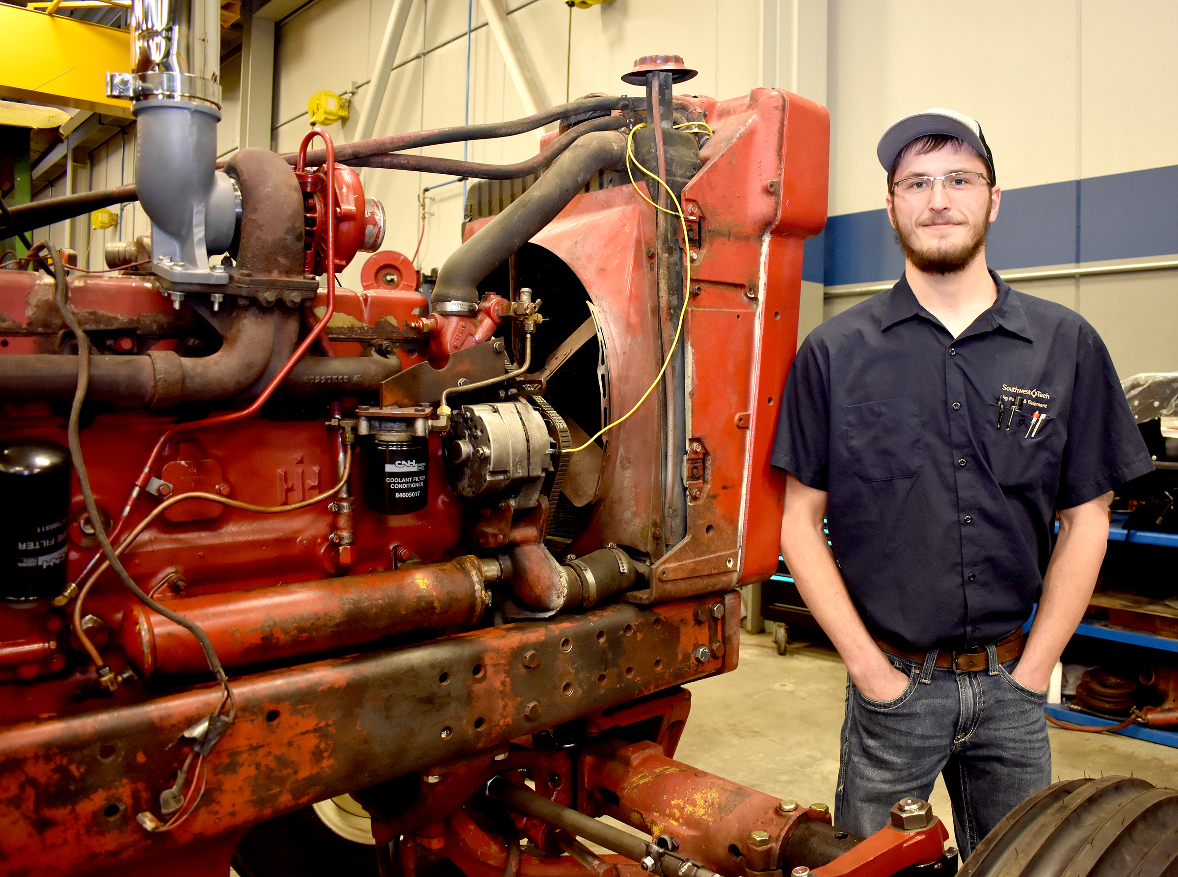 Male ag student standing next to farm machinery.