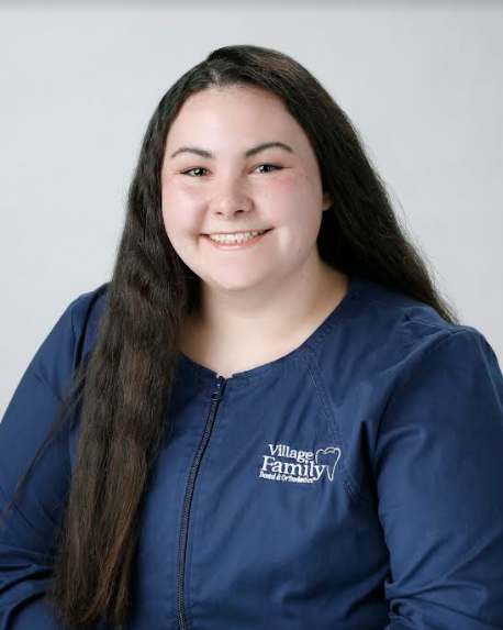 Female student with long hair, wearing blue scrubs.