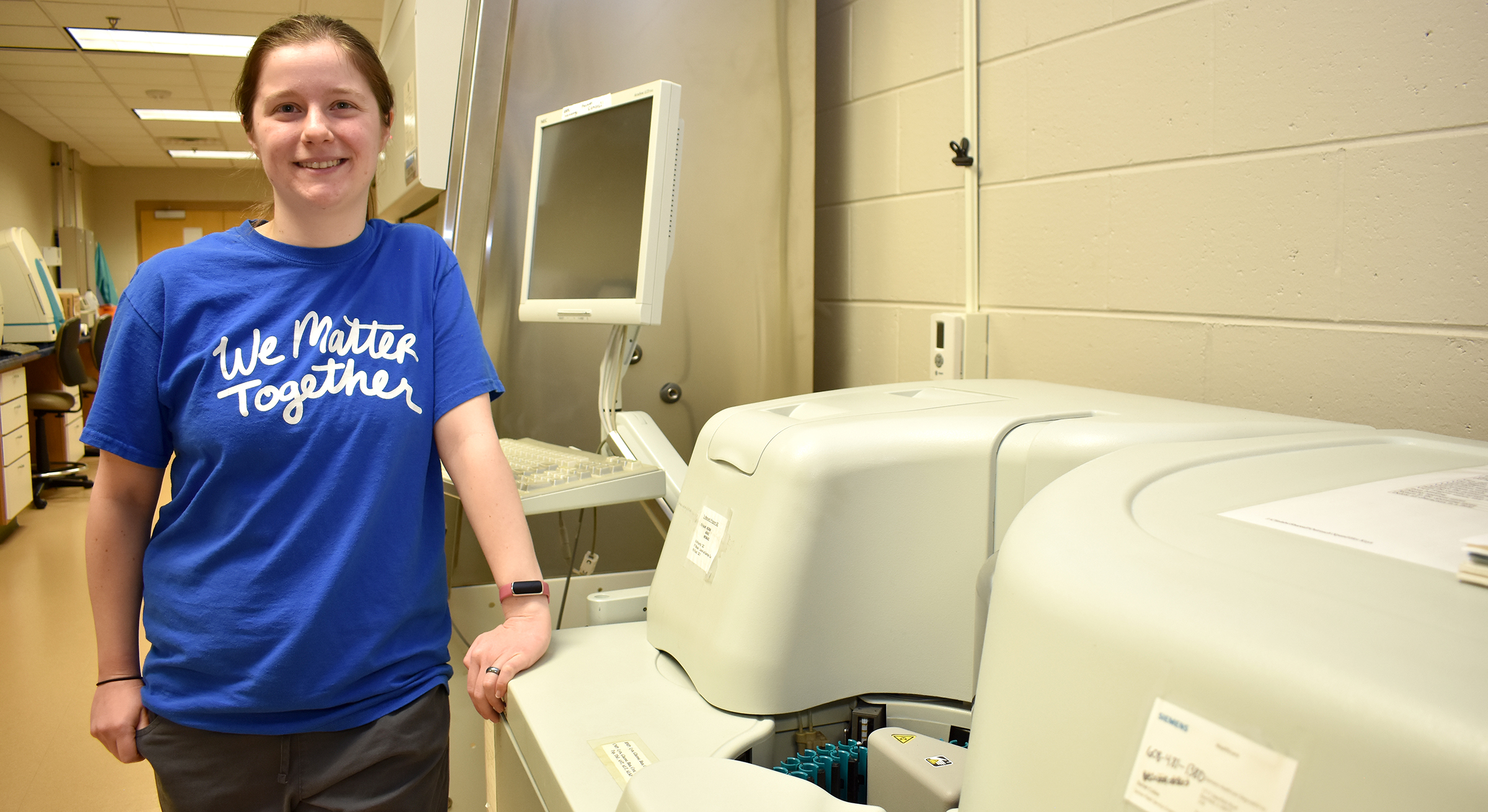 Female student standing next to medical lab equipment.