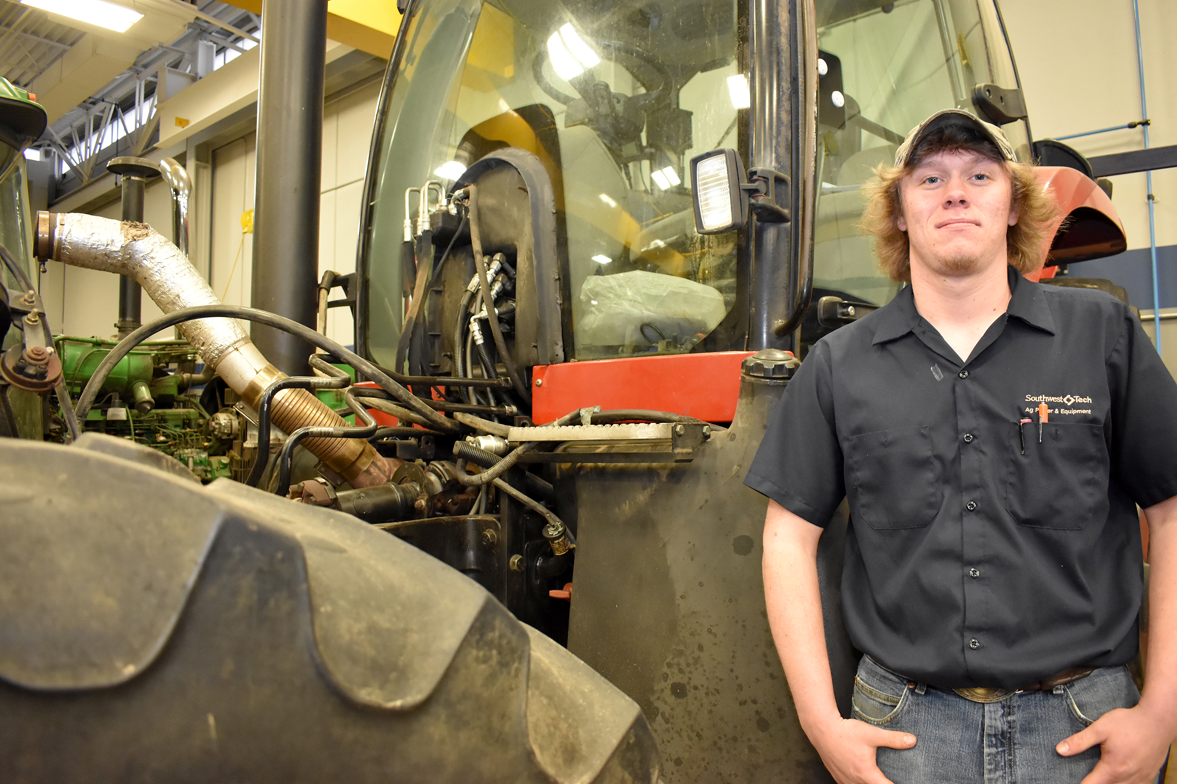 Male student standing in front of tractor cab.