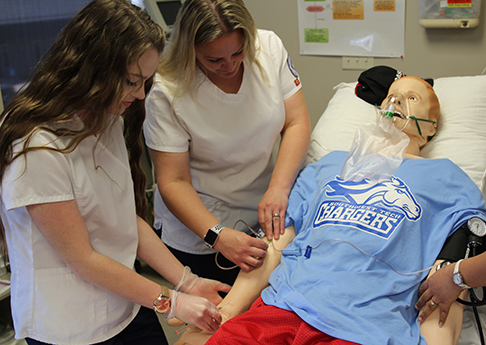 Nusing students work on a lifelike human patient simulator.